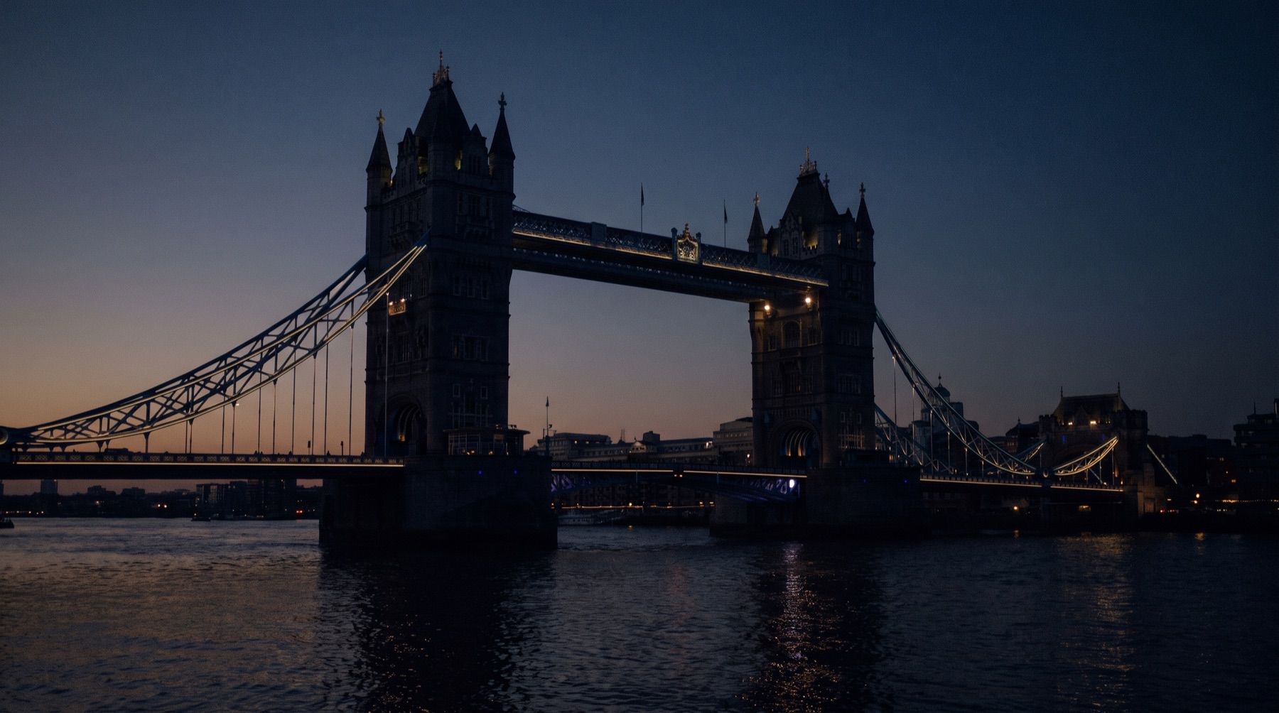 Tower Bridge in London at dusk, its walkways traced in warm golden light